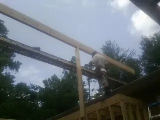 Carpenter setting a ridge beam over a new addition frame — Ice Dam Removal by Roofing Brothers in Harbert