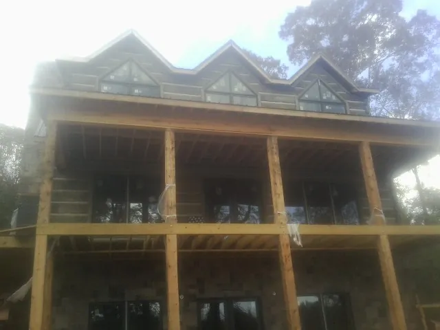 Dormers and porch framing on a large log home under construction — Roof Coating work by our crew in Harbert