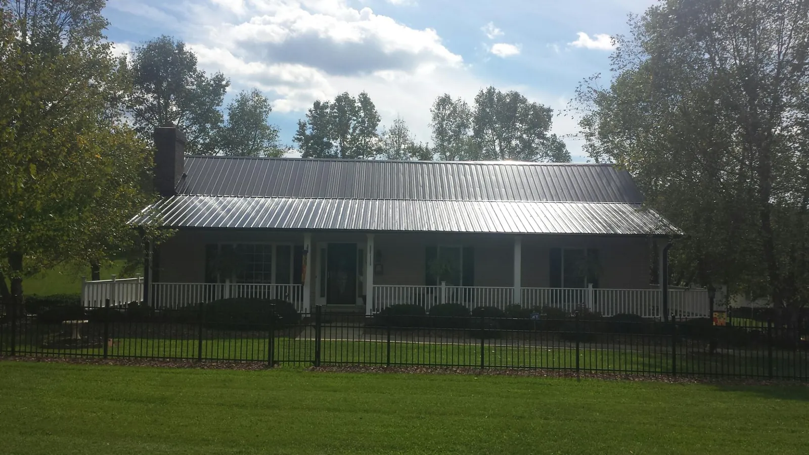Gray metal roof on a brick ranch with a full width front porch — Gutter Guard Installation work by our crew in Harbert